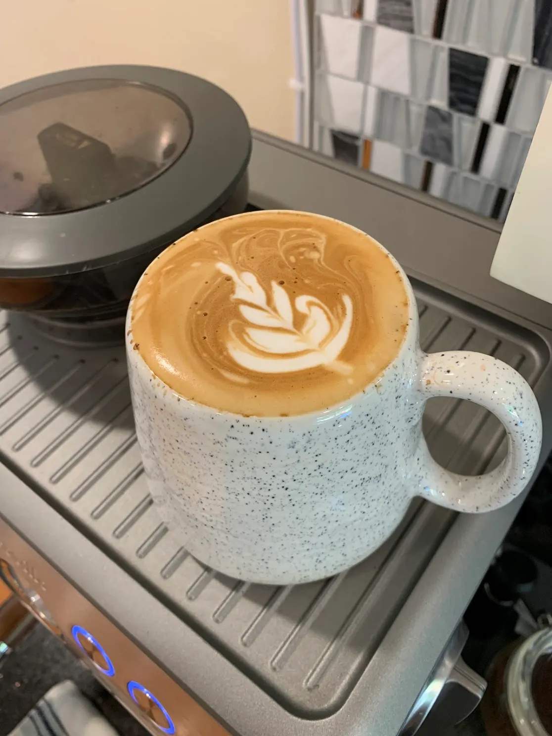 Latte with tulip art in speckled mug on espresso machine