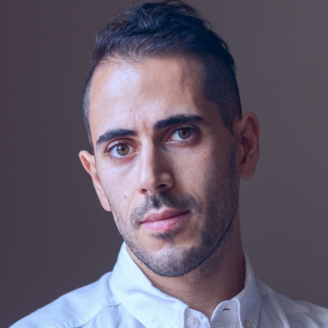 Mahdi Farra in a white collared shirt against a gray studio backdrop.